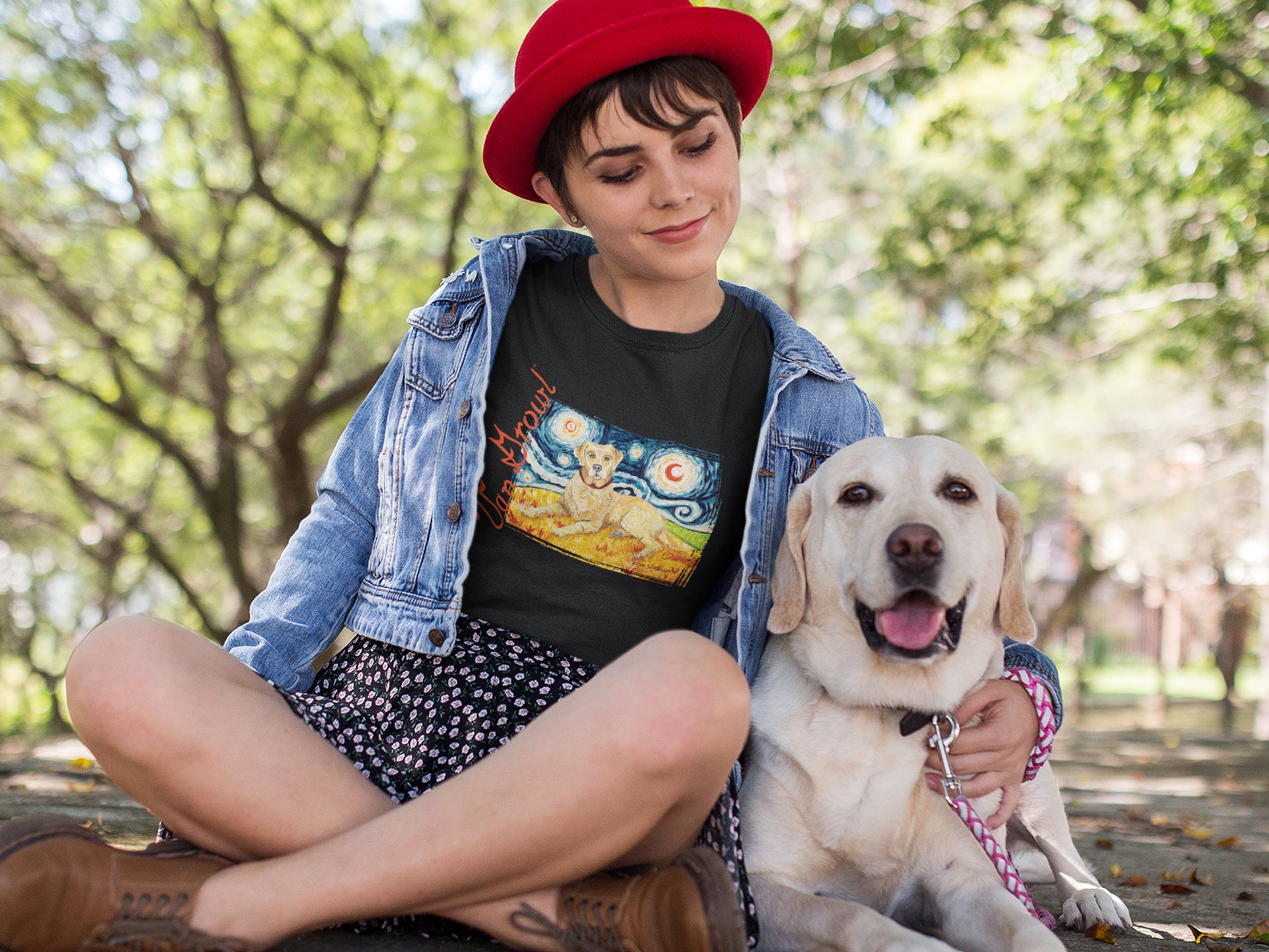 Girl wearing a red hat and a dog art t-shirt inspired by Van Gogh sitting with a Yellow Labrador.